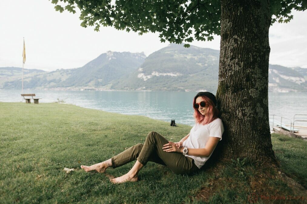 girl in sunglasses and hat resting near tree in bern switzerland
