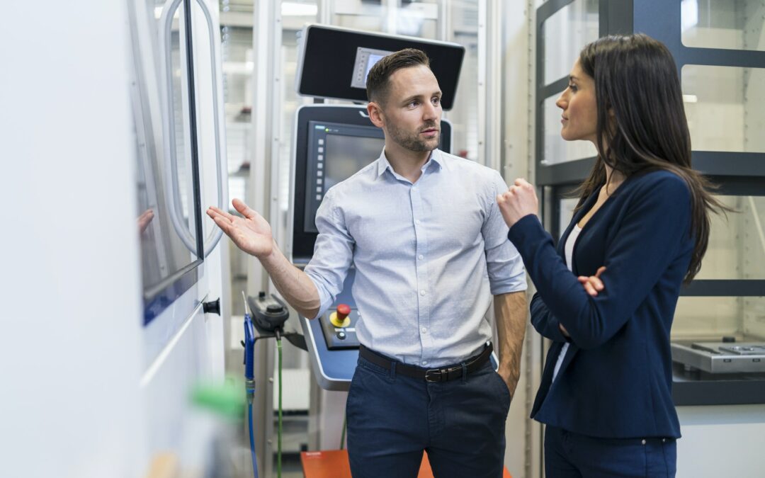 businessman and businesswoman talking at a machine in modern factory