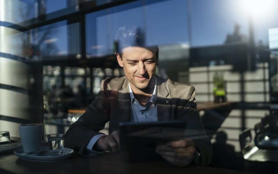 businessman using tablet behind the window in a cafe