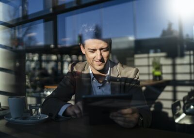 businessman using tablet behind the window in a cafe