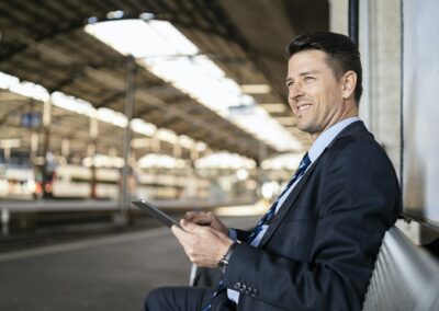Understanding Your Core Business - smiling businessman with tablet waiting on station platform